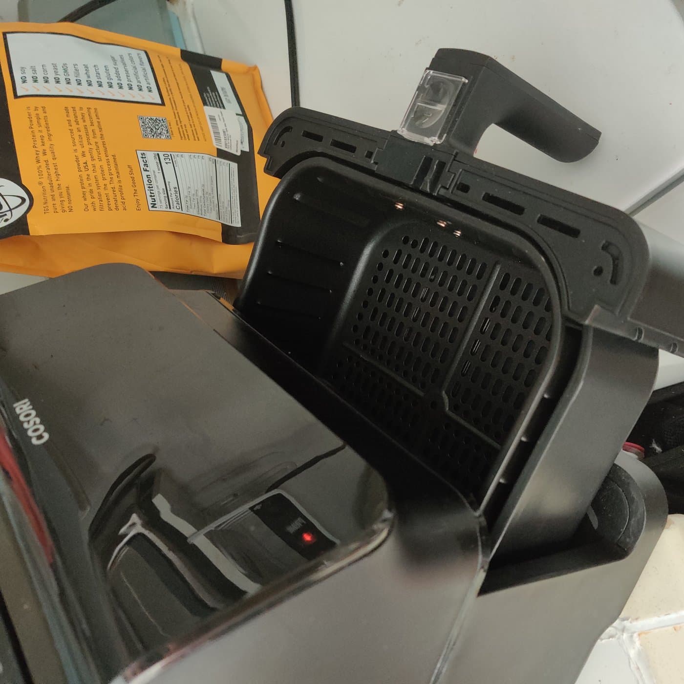 Air fryer basket pulled open showing nonstick interior and ventilation grates